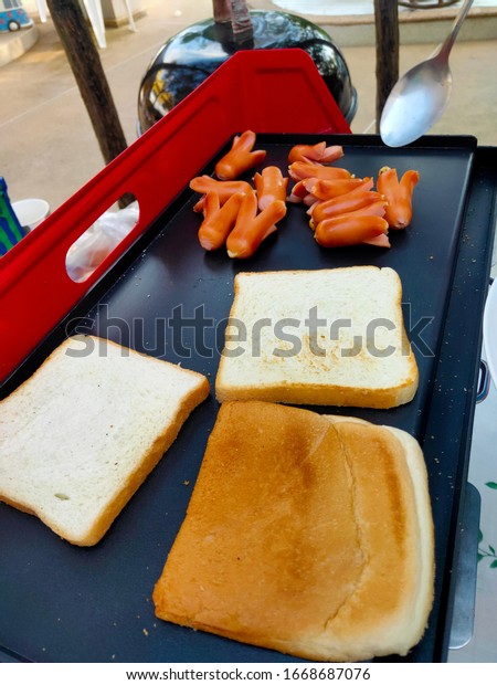 The most hearty and healthy outdoor\
camping breakfast, charcoal grilled sausages and\
bread.