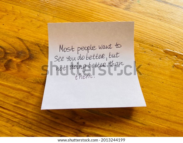 Most people want\
to see you do better, but not doing better than them! Handwritten\
message. Wooden\
background.