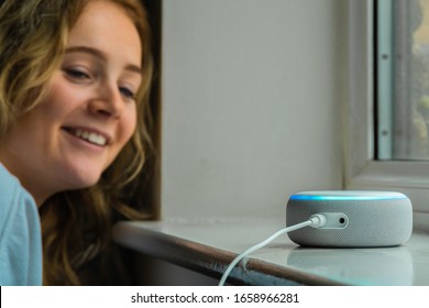 MOSTERTON ENGLAND FEBRUARY 2020 - Teenage girl talking to an Amazon Alexa Echo Dot. Girl smiling talking to an Alexa