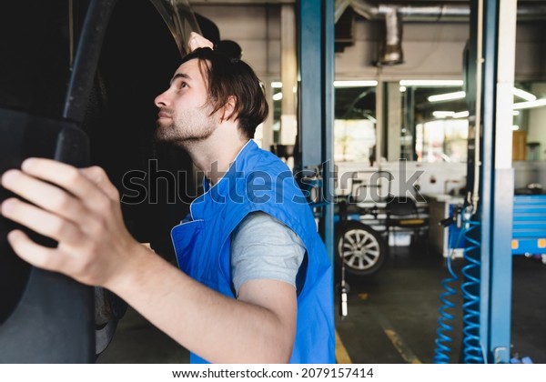 MOT. Vehicle inspection. Closeup caucasian\
handsome car auto technician mechanic fixing repairing car\
automobile before test\
drive.