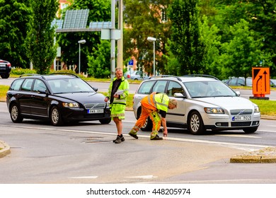 Motala, Sweden -June 21, 2016: Two Men Marking The Road For Future Roadwork. One Has A Notepad And The Other Spray Paint The Asphalt. Cars And Traffic Close To Them.