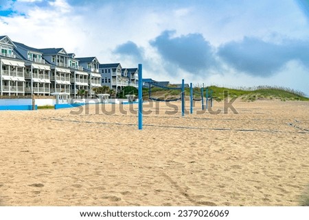 Motel and beach with volleyball courts on the shores of the Atlantic Ocean under a cloudy sky.
