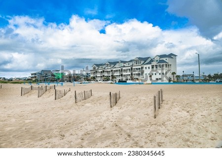 Motel and beach with volleyball courts on the shores of the Atlantic Ocean under a cloudy sky.