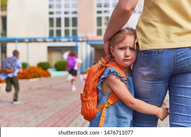 mother accompanies the child to school. mom supports and motivates the student. the little girl does not want to leave her mother. fears primary school. communication problems. attachment to parents. - Shutterstock ID 1476711077