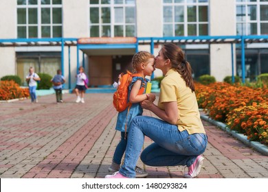 mother accompanies the child to school. mom supports and motivates the student.caring mother gently kisses her daughter on the forehead. positive little girl fun going to primary school.back to school