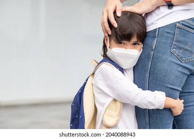 Mother Accompanies The Child To School. Mom Supports And Motivates The Student. The Little Girl Wearing A Face Mask Does Not Want To Leave Her Mother. Fears Primary School.