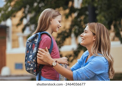 Mother accompanies the child to school. Mom supports and motivates the student.caring mother gently kisses her daughter on the forehead. Positive little girl fun going to primary school.Back to school - Powered by Shutterstock