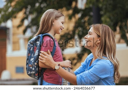 Mother accompanies the child to school. Mom supports and motivates the student.caring mother gently kisses her daughter on the forehead. Positive little girl fun going to primary school.Back to school