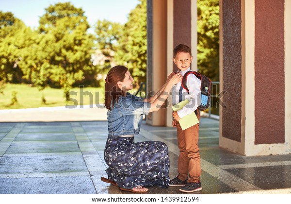 mother accompanies the child to school. mom\
encourages the student to accompany him to school. a caring mother\
looks tenderly at her son going to school.positive boy having fun\
going to primary school
