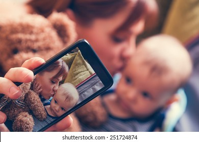 Mother And Adorable Baby Boy In Suitcase Taking Selfie While They Are Getting Ready For Traveling - Powered by Shutterstock