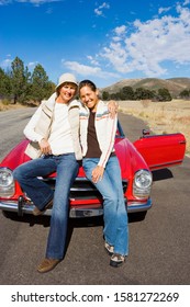 Mother And Adult Daughter With Classic Red Convertible Car On Road