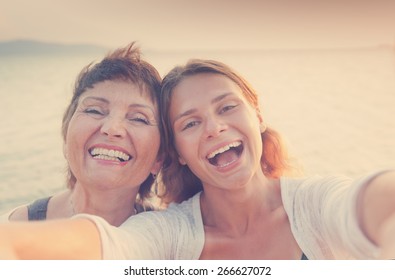 Mother And Adult Daughter Are Doing Selfe On The Beach