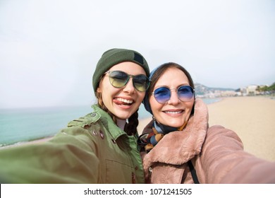 Mother And Adult Daughter Are Doing Selfie On The Beach In Barcelona, Going Crazy And Showing Tongue.Happy And Positive Emotions.Hipster Family.Parents And Teenagers.Tourist Vacation Self-portrait