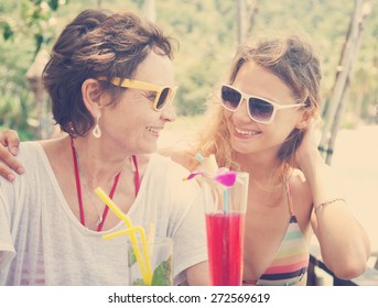 mother and adult daughter drink cocktails in the cafe