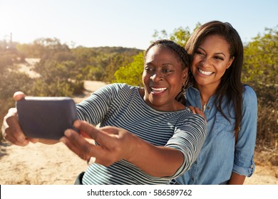 Mother And Adult Daughter Taking Selfie With Phone On Walk - Powered by Shutterstock