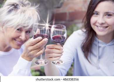 Mother And Adult Daughter Tasting Wine Sitting Outdoor