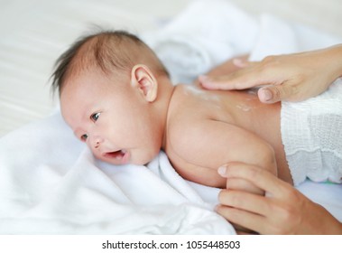 Mother are applying a lotion cream on the baby body after bath. Baby Care Concept.