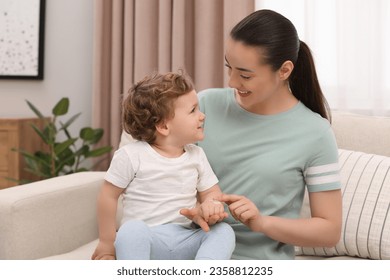 Mother applying ointment onto her son`s hand on sofa at home - Powered by Shutterstock