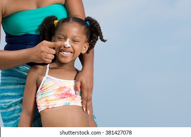 Mother Applying Suncream To Daughters Nose