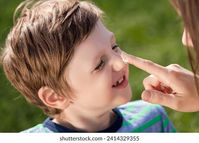 Mother applying suncream on son's nose - Powered by Shutterstock