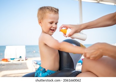 Mother applying sunscreen protection creme on cute little baby boy kid hand. Mum using sunblocking lotion to protect baby from sun during summer sea vacation. Child healthcare travel vacation time
