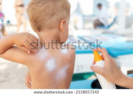 Mother applying sunscreen protection creme on cute little baby boy kid hand. Mum using sunblocking lotion to protect baby from sun during summer sea vacation. Child healthcare travel vacation time