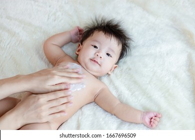 Mother Applying Talcum Powder To Her Infant Baby.