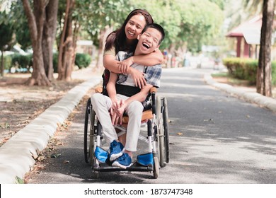 Mother And Asian Disabled Child On Wheelchair Is Playing, Learning And Exercise In The Outdoor City Park Like Other People With Family,Life In The Education Age,Happy Disability Kid Concept.