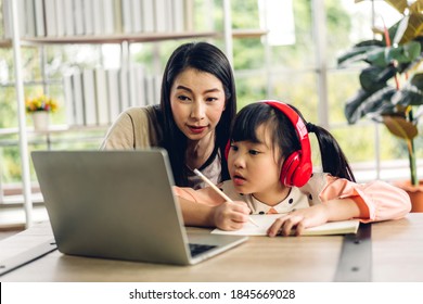 Mother and asian kid little girl learning and looking at laptop computer making homework studying knowledge with online education e-learning system.children video conference with teacher tutor at home - Powered by Shutterstock