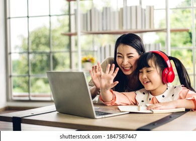 Mother And Asian Kid Little Girl Learning And Looking At Laptop Computer Making Homework Studying With Online Education E-learning System.children Video Conference With Teacher Tutor At Home