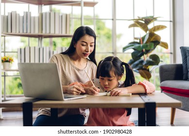 Mother And Asian Kid Little Girl Learning And Looking At Laptop Computer Making Homework Studying Knowledge With Online Education E-learning System.children Video Conference With Teacher Tutor At Home