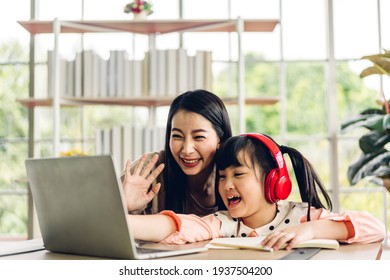 Mother And Asian Kid Little Girl Learning And Looking At Laptop Computer Making Homework Studying Knowledge With Online Education E-learning System.children Video Conference With Teacher Tutor At Home