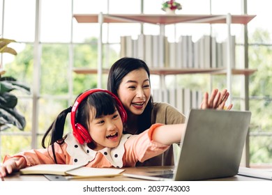 Mother And Asian Kid Little Girl Learning And Looking At Laptop Computer Making Homework Studying With Online Education E-learning System.children Video Conference With Teacher Tutor At Home