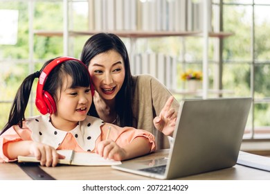 Mother And Asian Kid Little Girl Learning And Looking At Laptop Computer Making Homework Studying With Online Education E-learning System.children Video Conference With Teacher Tutor At Home