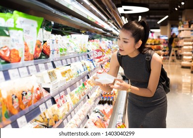 Mother Asian Working Woman Select Pick Up Healthy Nutrition Food, Yogurt Milk From Supermarket Shelf Rack After Work. Concept Decision Making Choice Select Best Thing For Kid Children Family