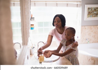 Mother assisting daughter while washing hands in bathroom at home, Coronavirus hand washing for clean hands hygiene Covid19 spread prevention