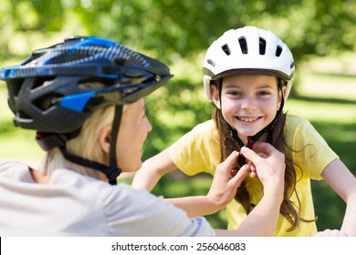 Mother Attaching Her Daughters Cycling Helmet On A Sunny Day