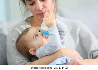 Mother And Baby Boy Holding Baby Bottle