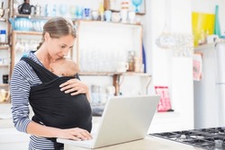 Mother With Baby Boy Using Laptop In Kitchen