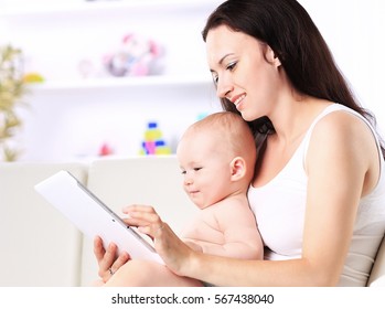 mother and baby child are looking to play  read tablet computer - Powered by Shutterstock