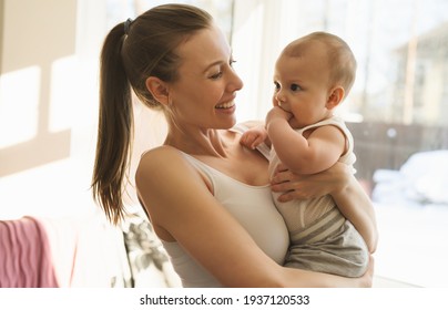 Mother And Baby Close-up. Mom Holds The Child In Her Arms, Hugs Him And Kisses Him. Happy Family Concert. High Quality Photo