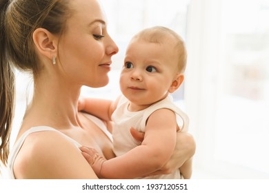 Mother And Baby Close-up. Mom Holds The Child In Her Arms, Hugs Him And Kisses Him. Happy Family Concert. High Quality Photo