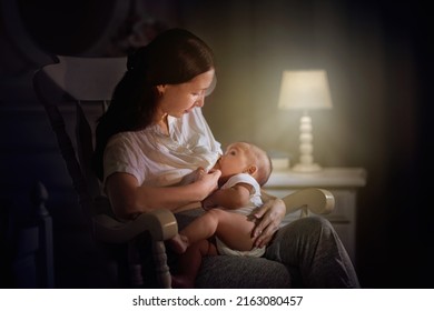 Mother and baby in dark bedroom. Asian mom with newborn boy in white rocking chair at night. Breastfeeding and infant care. Happy family at home. Bedtime and midnight feeding. - Shutterstock ID 2163080457