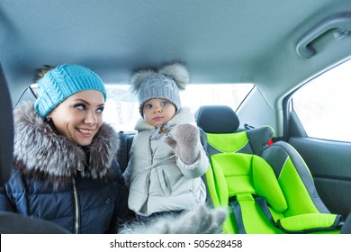 Mother And Baby Daughter Bask In The Car After A Walk In A Winter Park. Happy Family. Childhood And Parenthood Happiness.