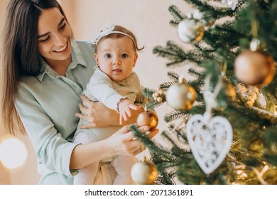 Mother With Baby Daughter Dacorating Christmas Tree