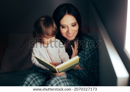 Similar – Mother reading book to her sons in the bed