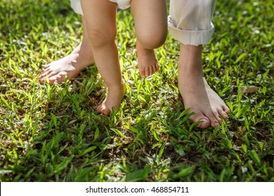 Mother And Baby Feet Walking On Grass