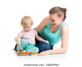 Mother and baby girl having fun with musical toy. Isolated on white background