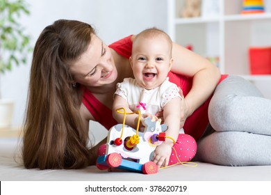 Mother and baby girl playing with toy in living room