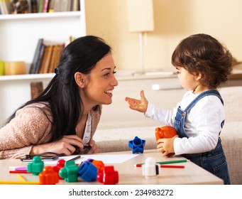 Mother and baby girl playing with toys in living room.